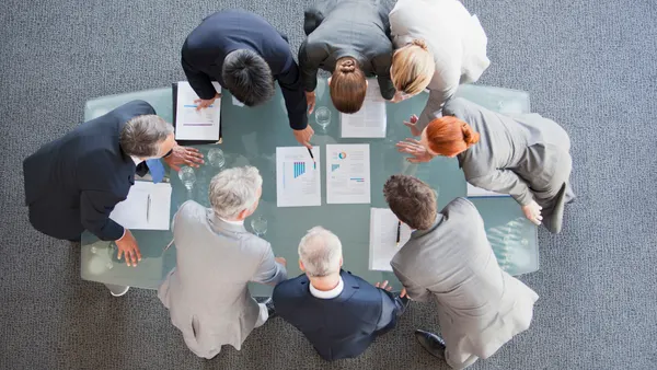 Business people huddled around paperwork on table