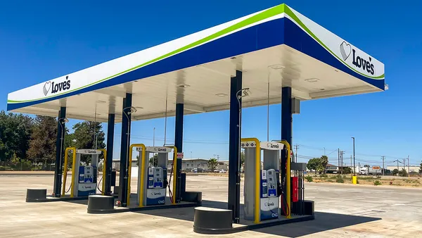 A photo of a compressed natural gas filling station under a white, blue and green canopy. The canopy says "Love's" on the two visible sides.