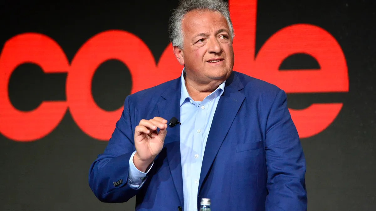 A person in a blue suit speaks at a lectern.