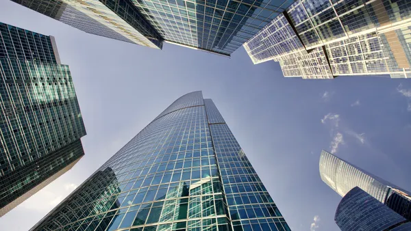 Office skyscrapers against bright sun and clear blue sky.