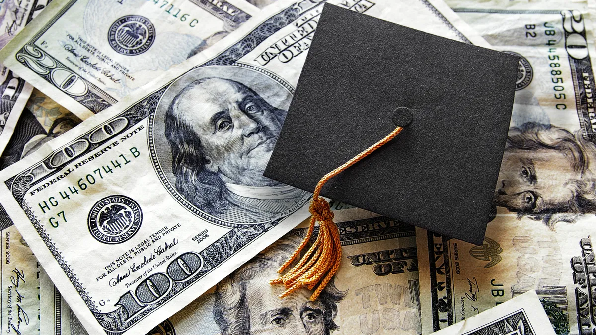 A graduation cap sits atop cash bills