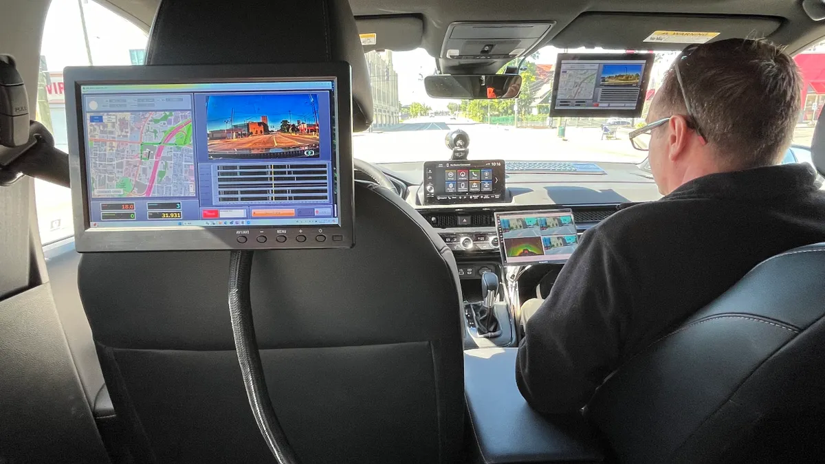 View from rear seat of a vehicle with a computer screen showing roadway map and conditions.
