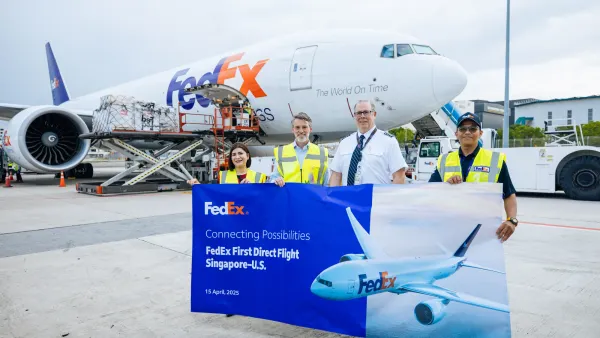 B777 freighter on a tarmac with four people holding signage about a new Singapore-U.S. air cargo route.