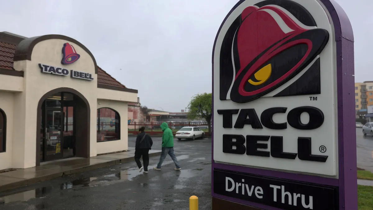 Two people walk towards a Taco Bell restaurant