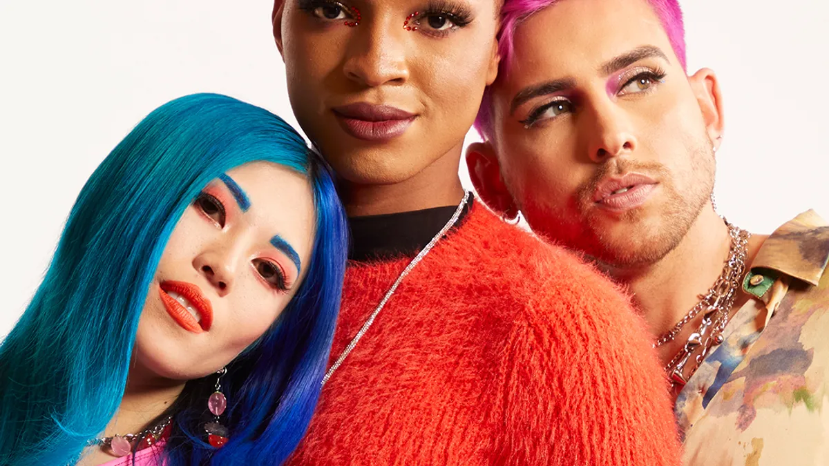 Three people with brightly colored makeup and hair pose together