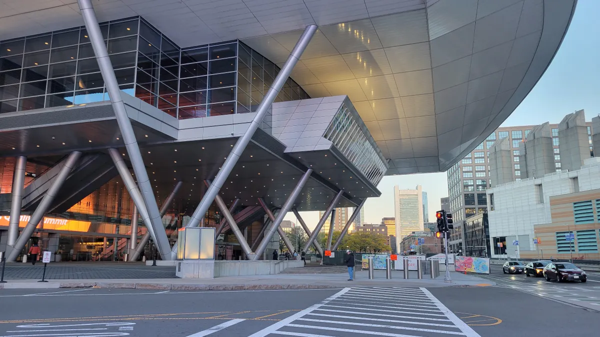 The exterior of a convention center at sunrise is viewed from across the street.