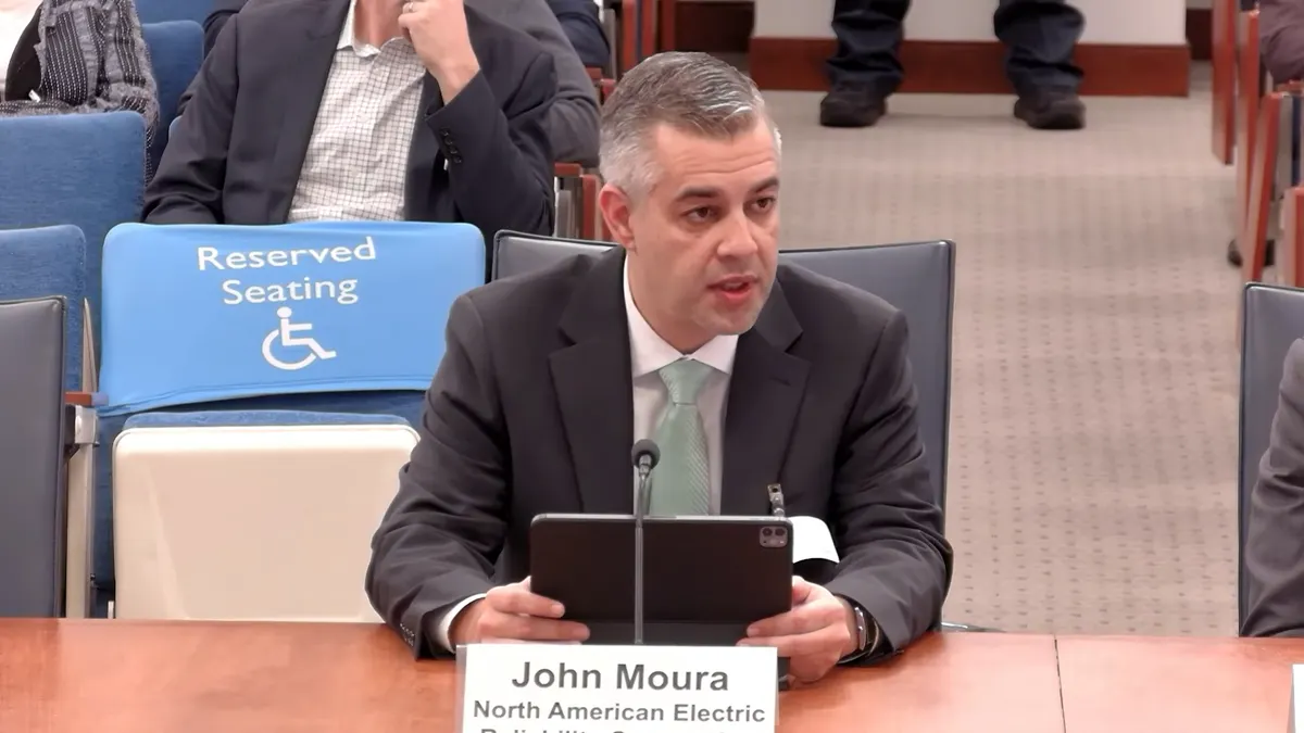 A man speaks from a desk.