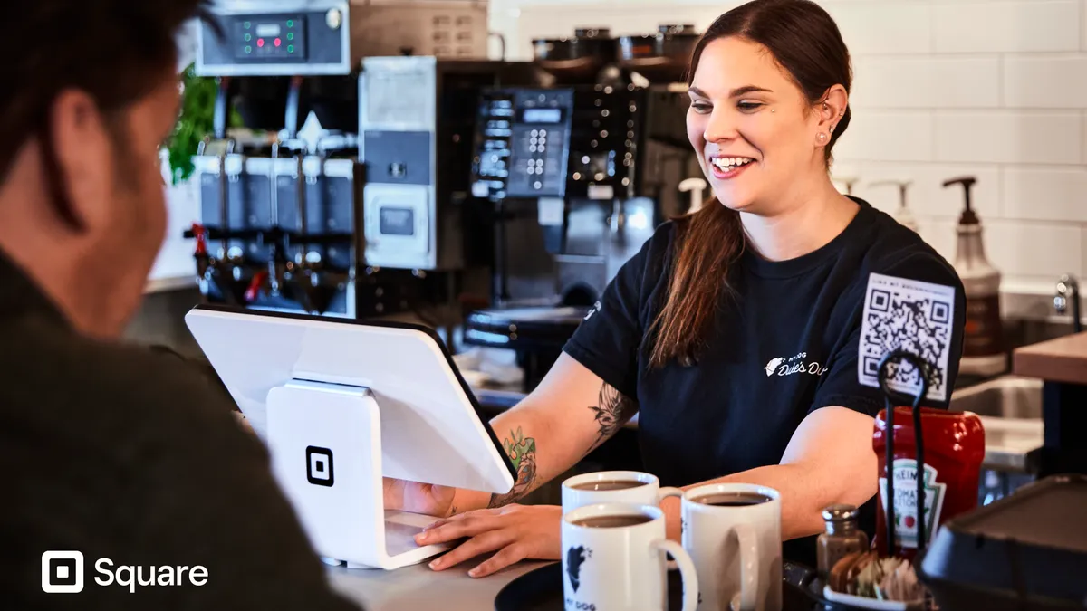 A restaurant worker serving someone at the counter on a Square mobile payment platform.