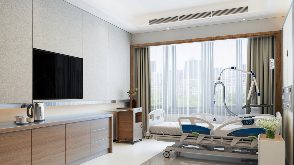 A modern hospital room interior with an empty bed, an LCD television and a city view from the window.