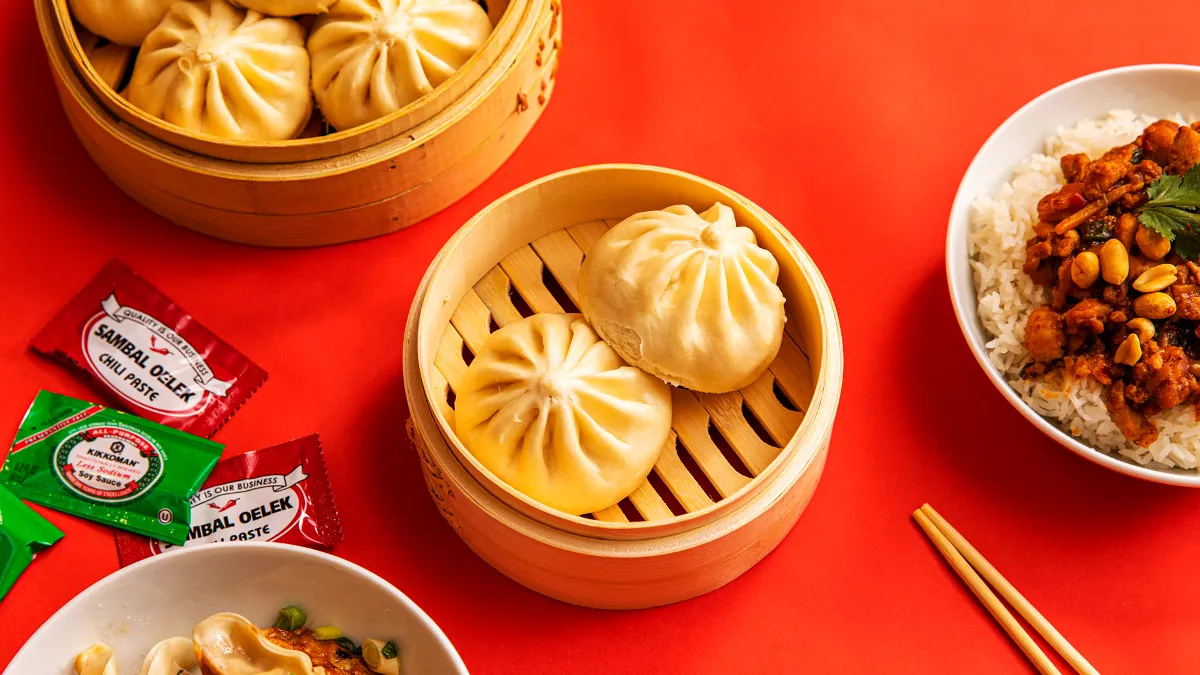 An image of various Asian food items in steamer bowls, like bao buns, rice