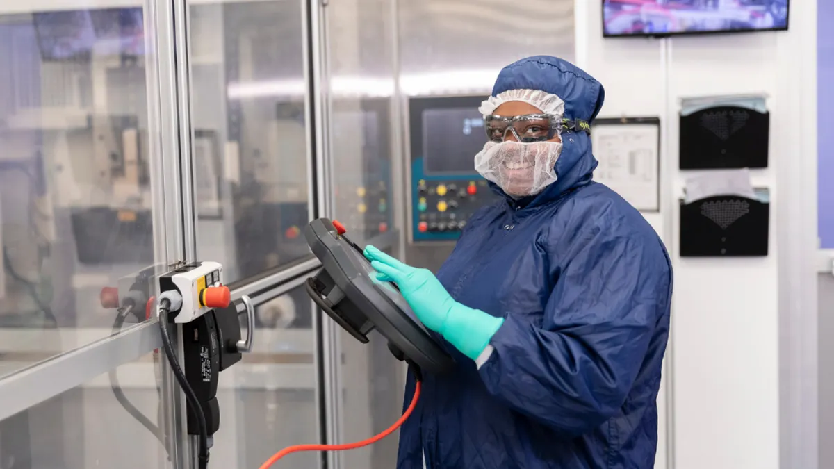 Lab worker all suited up in protective gear doing tests