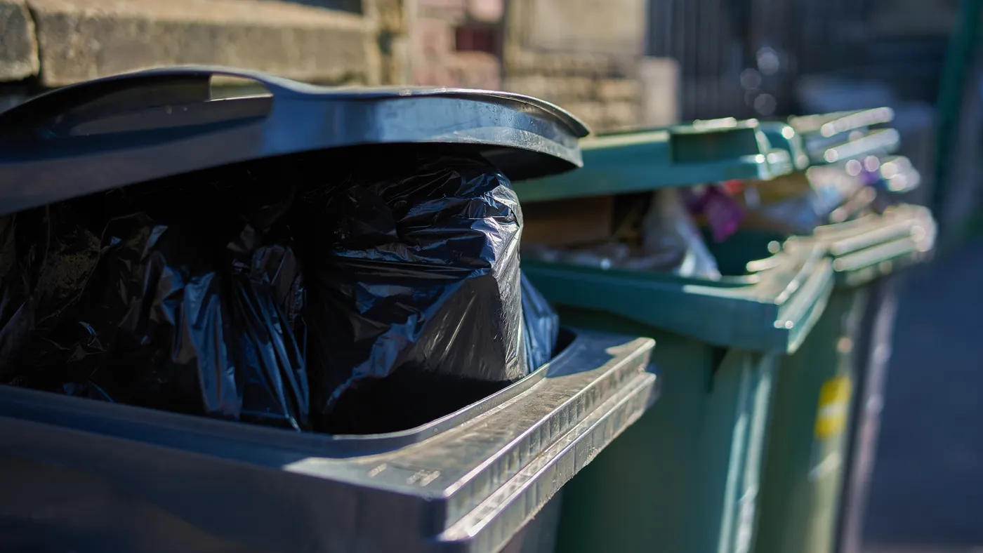 Gray and green garbage cans overfilled with domestic refuse