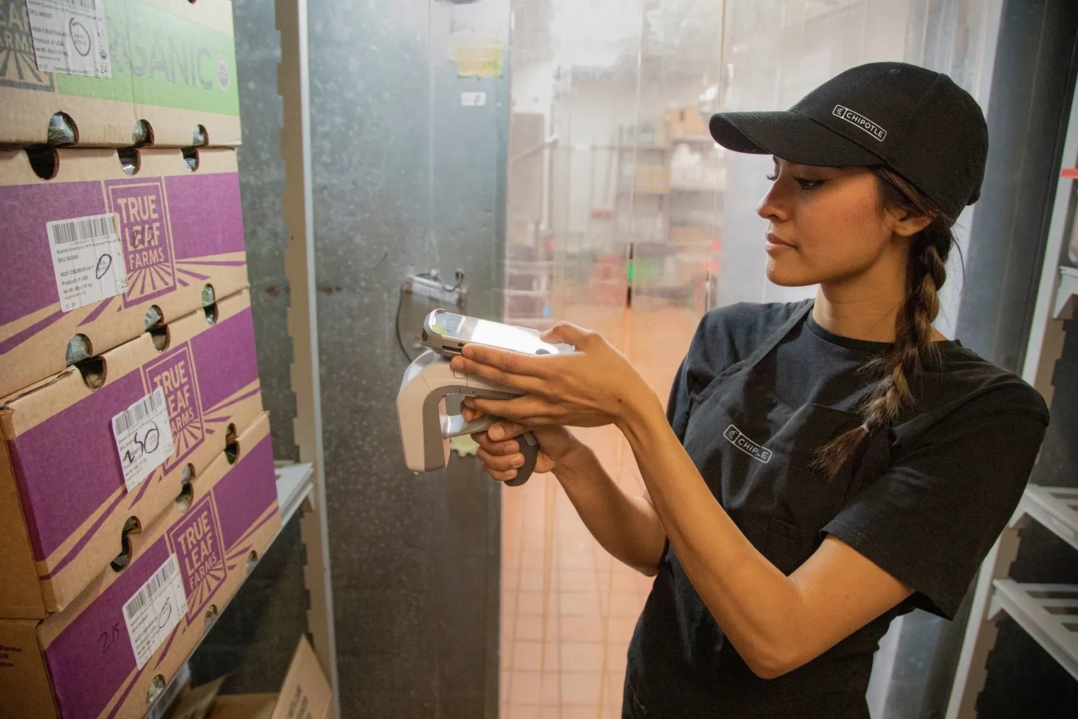 A restaurant employee using RFID to scan a box with a barcode.