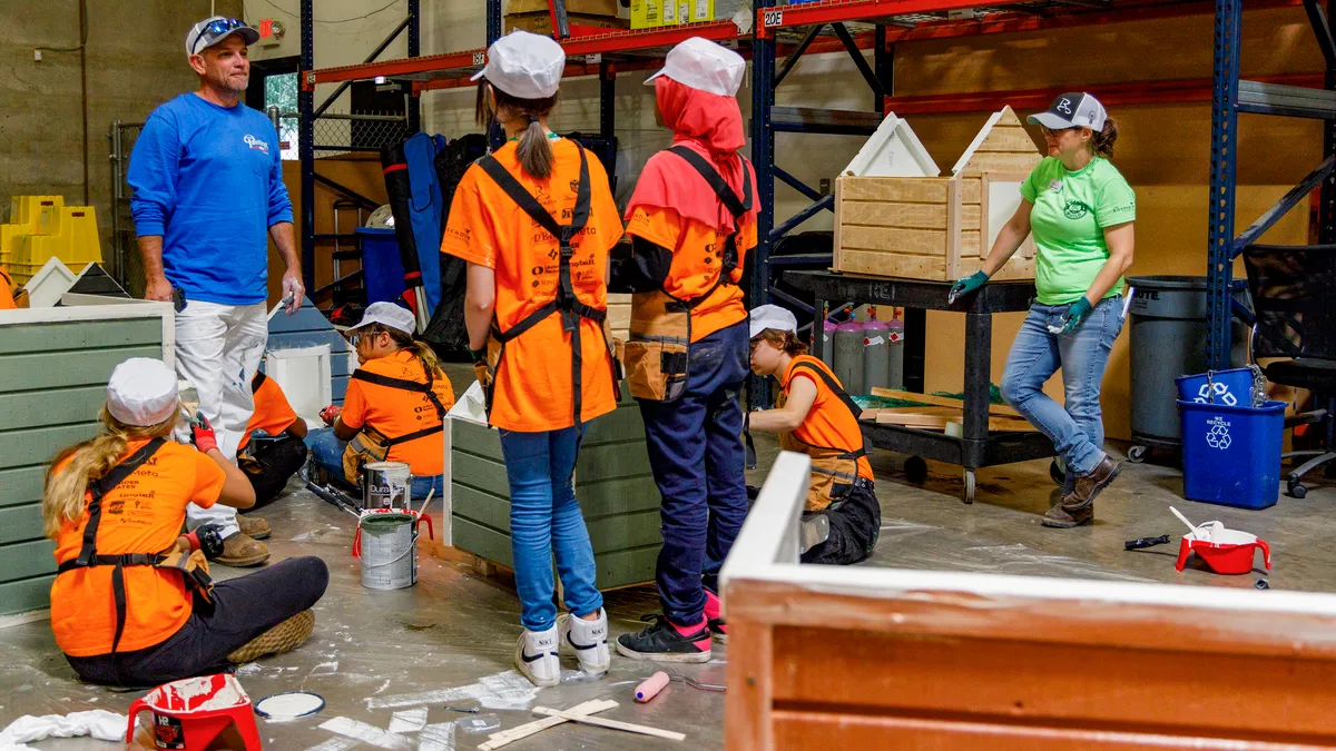 Children in brightly colored gear gather around an instructor in a workshop.