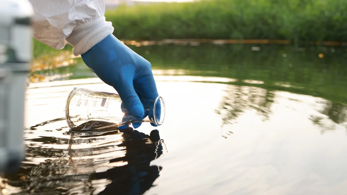 Environment engineer collect samples of wastewater from industrial canals in test tube.