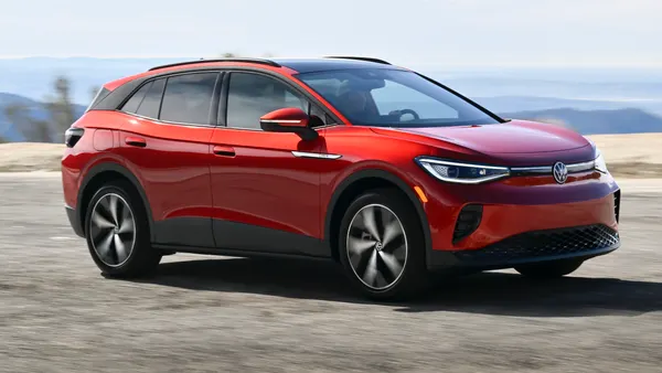 A red 2024 Volkswagen ID.4 electric SUV driving on a road.