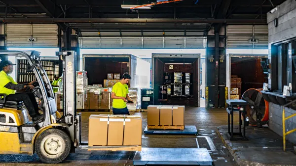 Warehouse employees use a freight dimensioning system to weigh cargo.