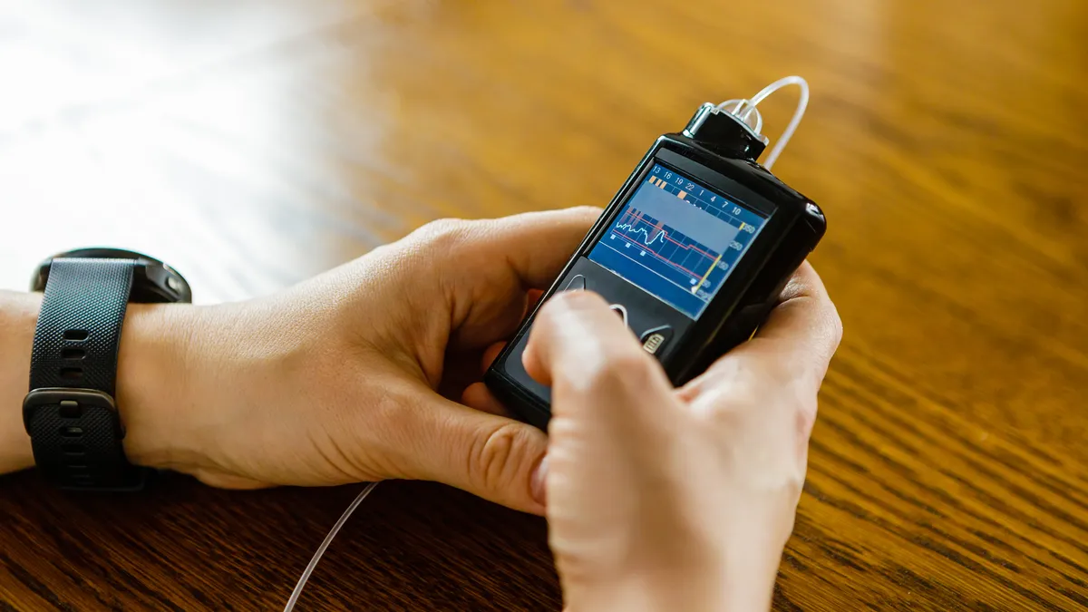 A person holds a rectangular device connected to tubing.