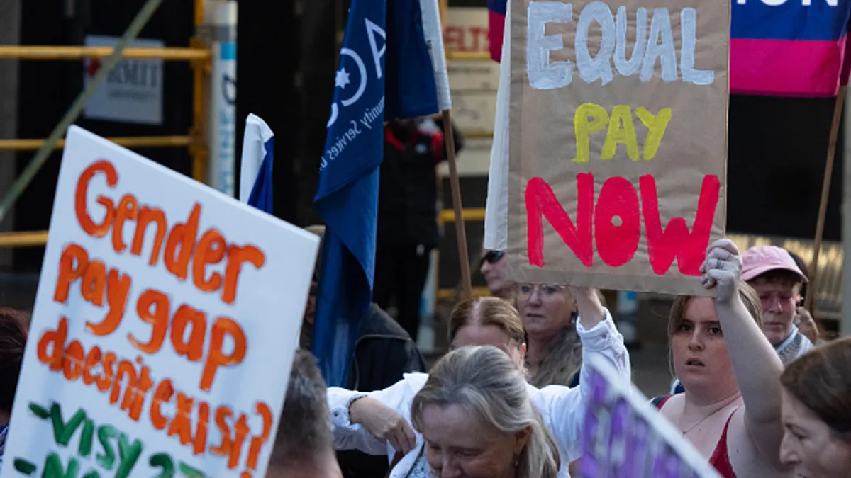 People hold signs about equal pay