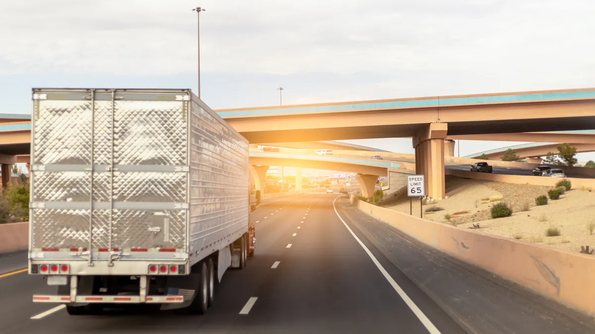 A tractor-trailer on a highway under an interchange.