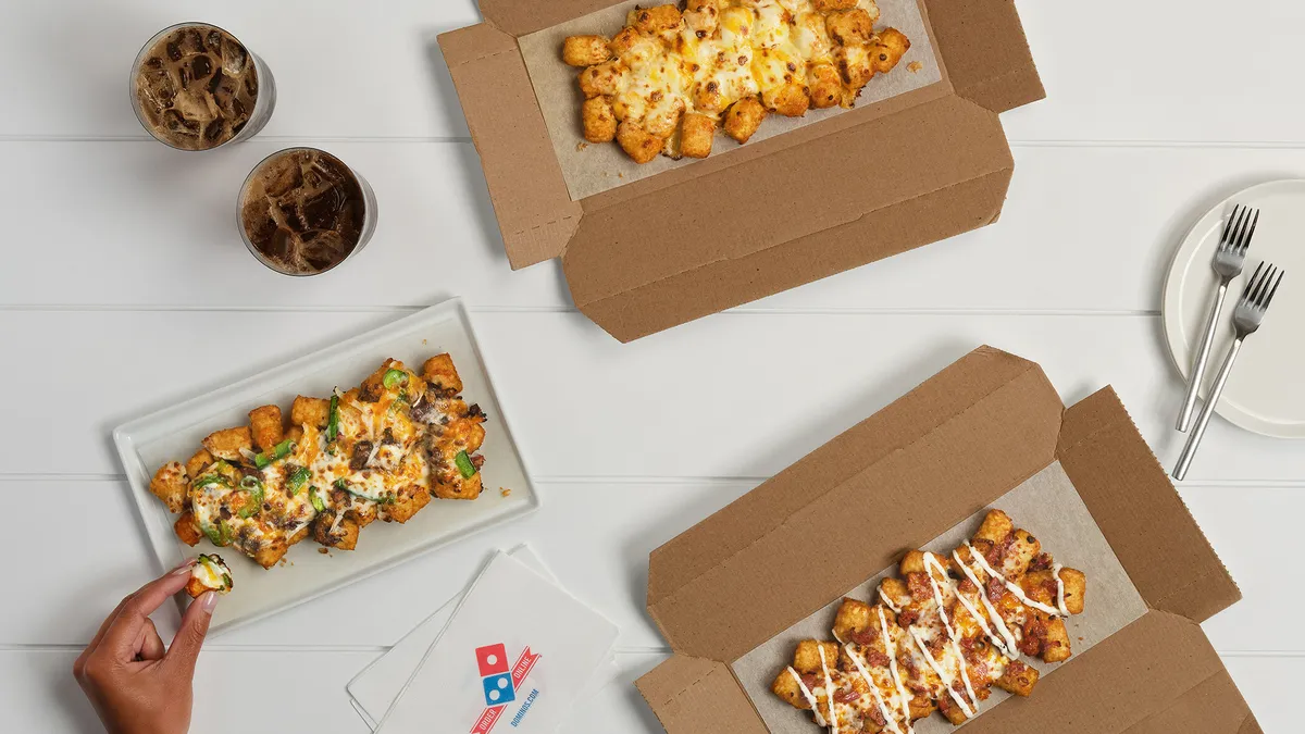 A promotional image showing three boxes of Domino's loaded tots.