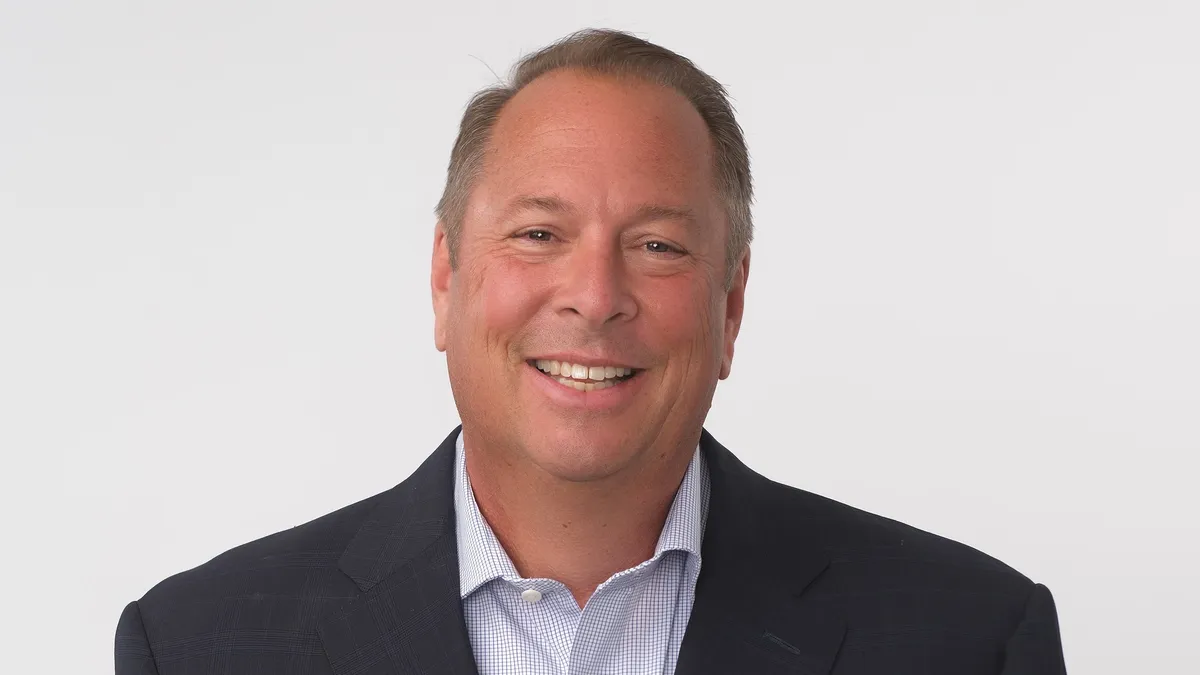 An image of a man in a suite in front of a light background