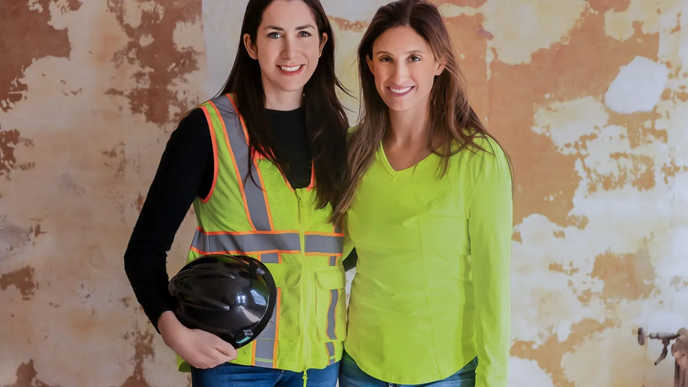 Two women post for a photograph together wearing personal protective equipment.