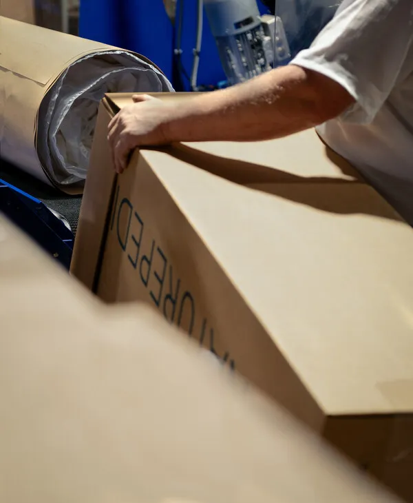 Paper packaging and a cardboard box with the Naturepedic logo.