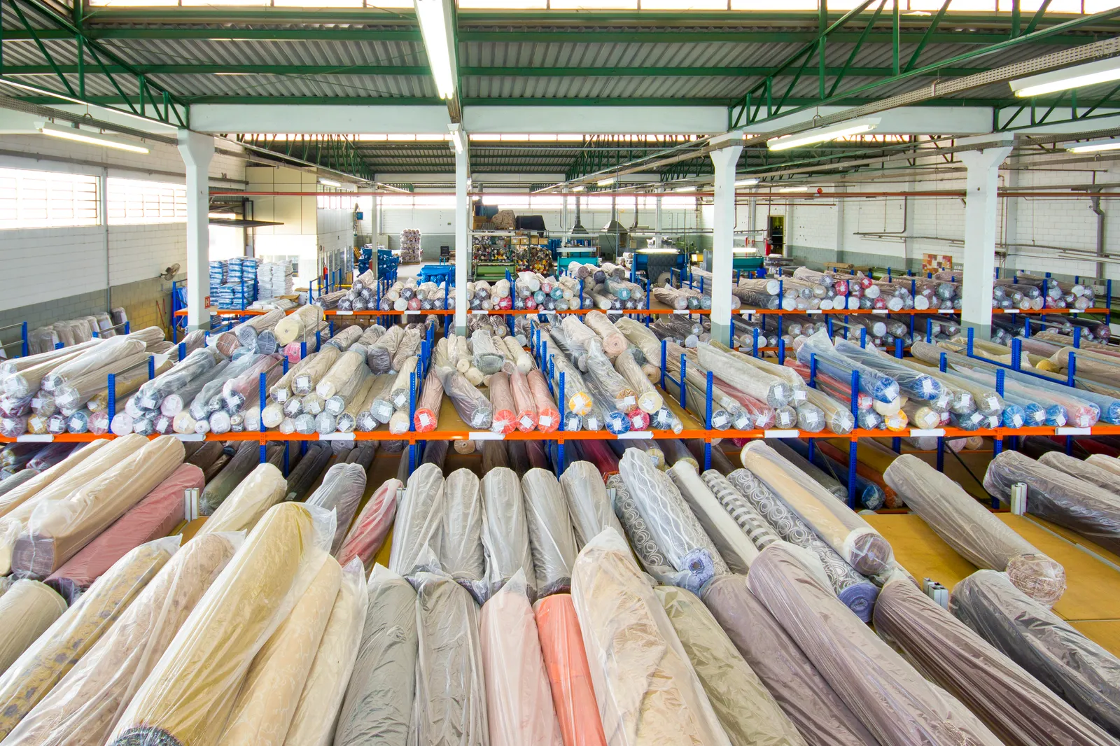 A warehouse filled with multiple rolls of fabric on shelving.