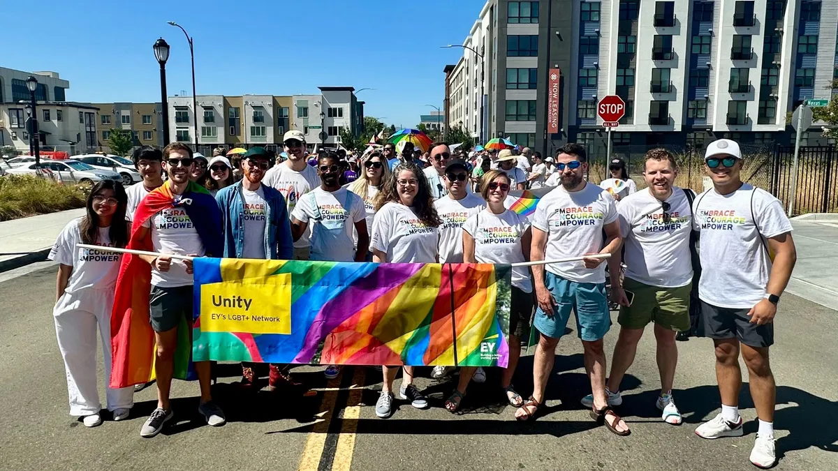 EY representatives carry a banner in a pride parade.