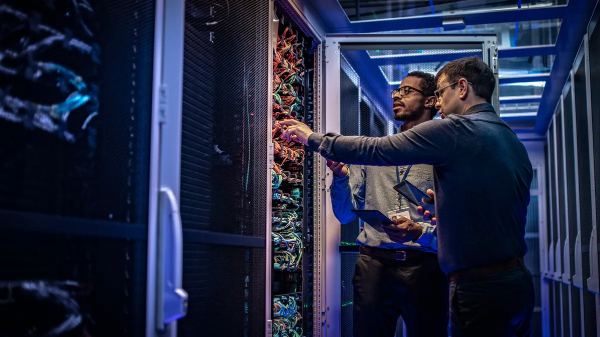 Two engineers look at a data center server rack.