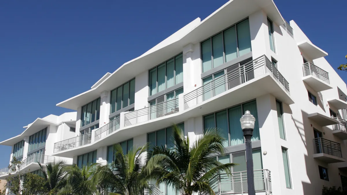 A condominium building with white walls and an angular roof.