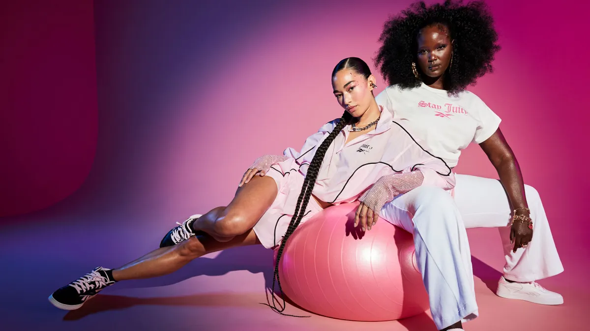 Two models pose in pink and white athleisure clothing and sneakers.