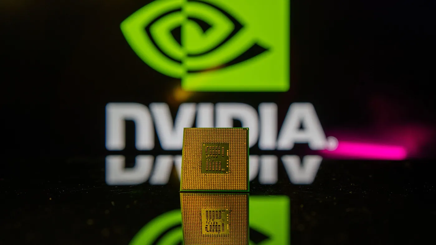 Close-up of a computer microchip GPU placed on a reflective surface, with intricate circuitry visible on the chip, and a blurred Nvidia logo glowing brightly in the green background.