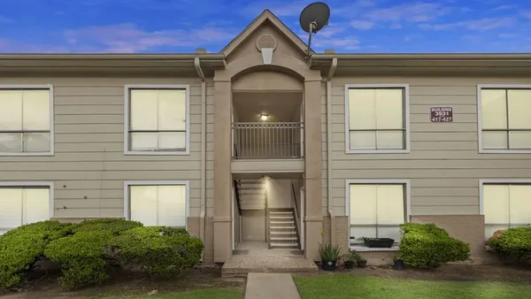 Two-level apartment building with grass in the front.