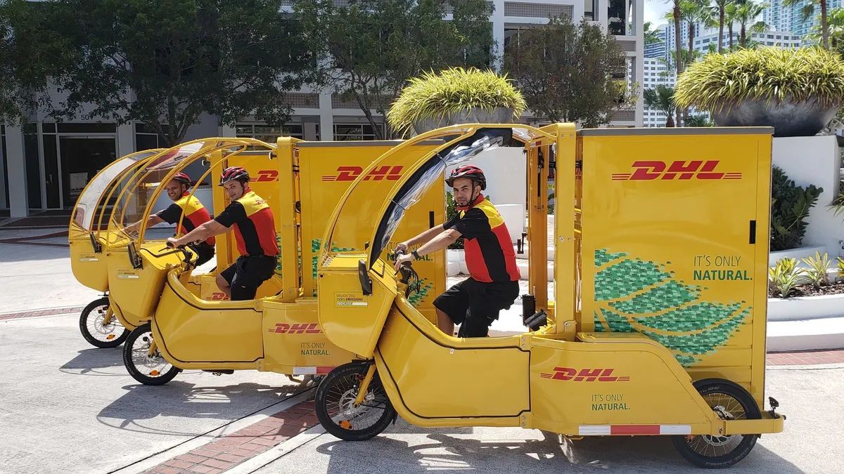 DHL couriers sit on cargo bikes.