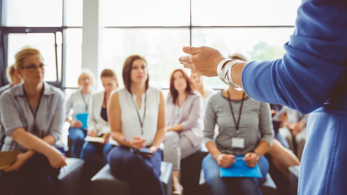 A group of teachers listen to a speaker.