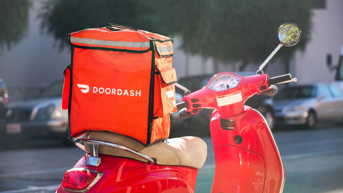 An image of a red scooter with a DoorDash bag on it.