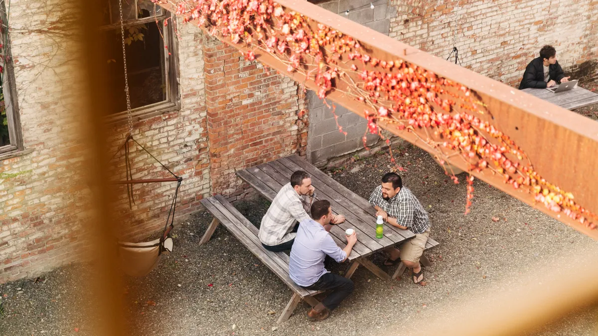 Employees sit at tables in an outdoor area at Etsy's Hudson office