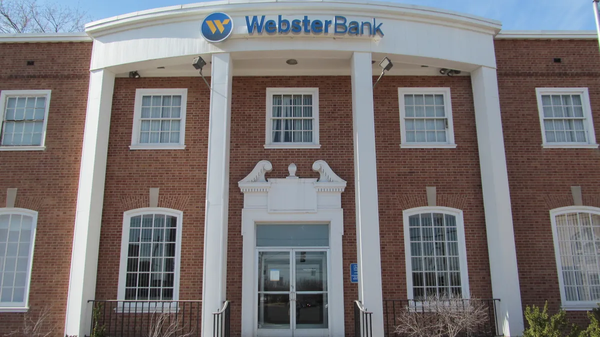 The front of a two-story brick bank building with the company name and logo.