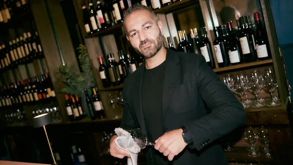 A worker in a fine restaurant cleaning a wine glass.