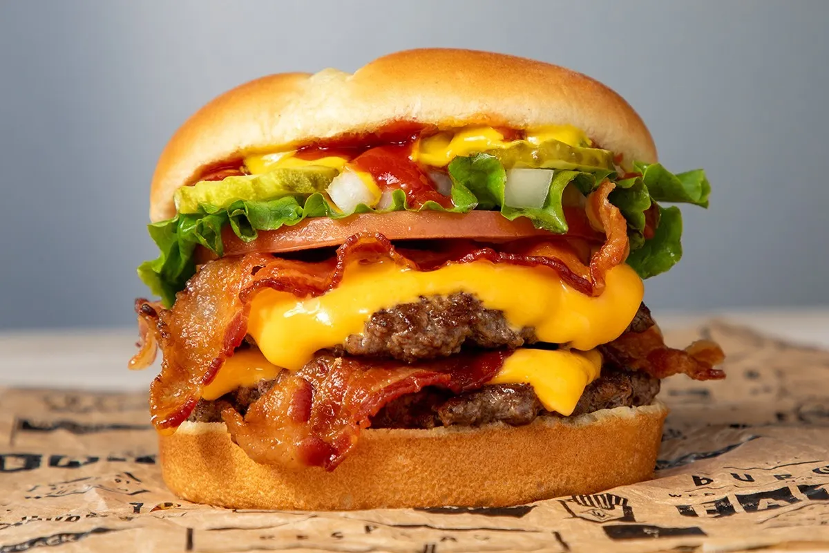 A close-up image of a double cheeseburger with bacon.