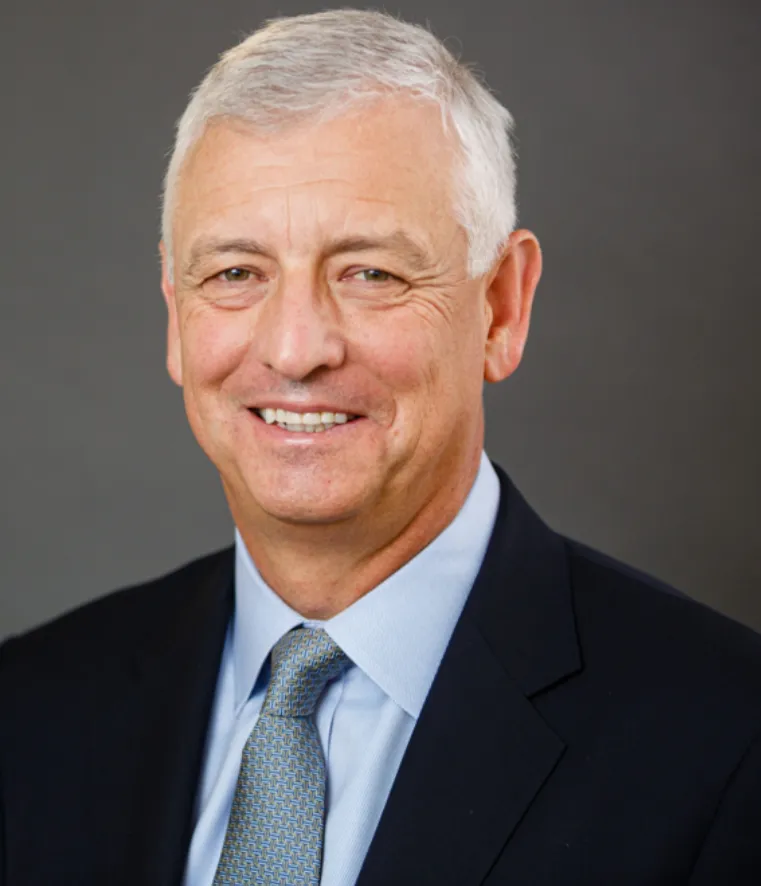 Headshot of a man with grey hair in a suit.