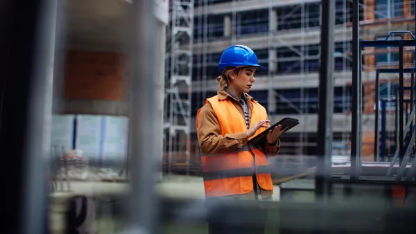 A construction worker uses a tablet at a jobsite.