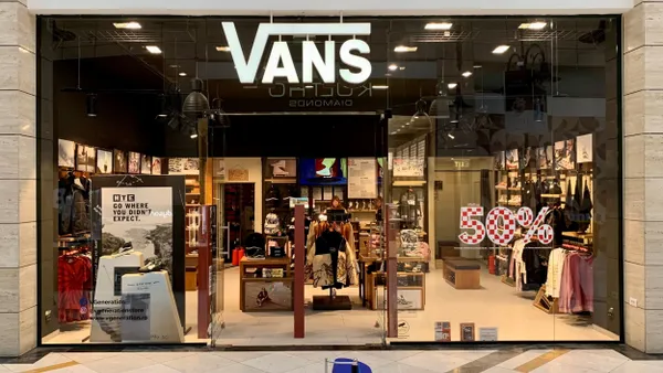 A Vans store is pictured in a mall, with a sign advertising a 50% off sale.