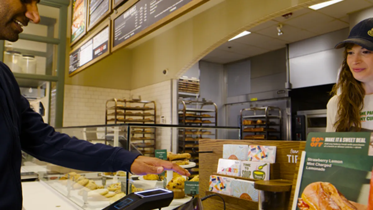 A customer scans his palm with an Amazon One device at a Panera cafe.