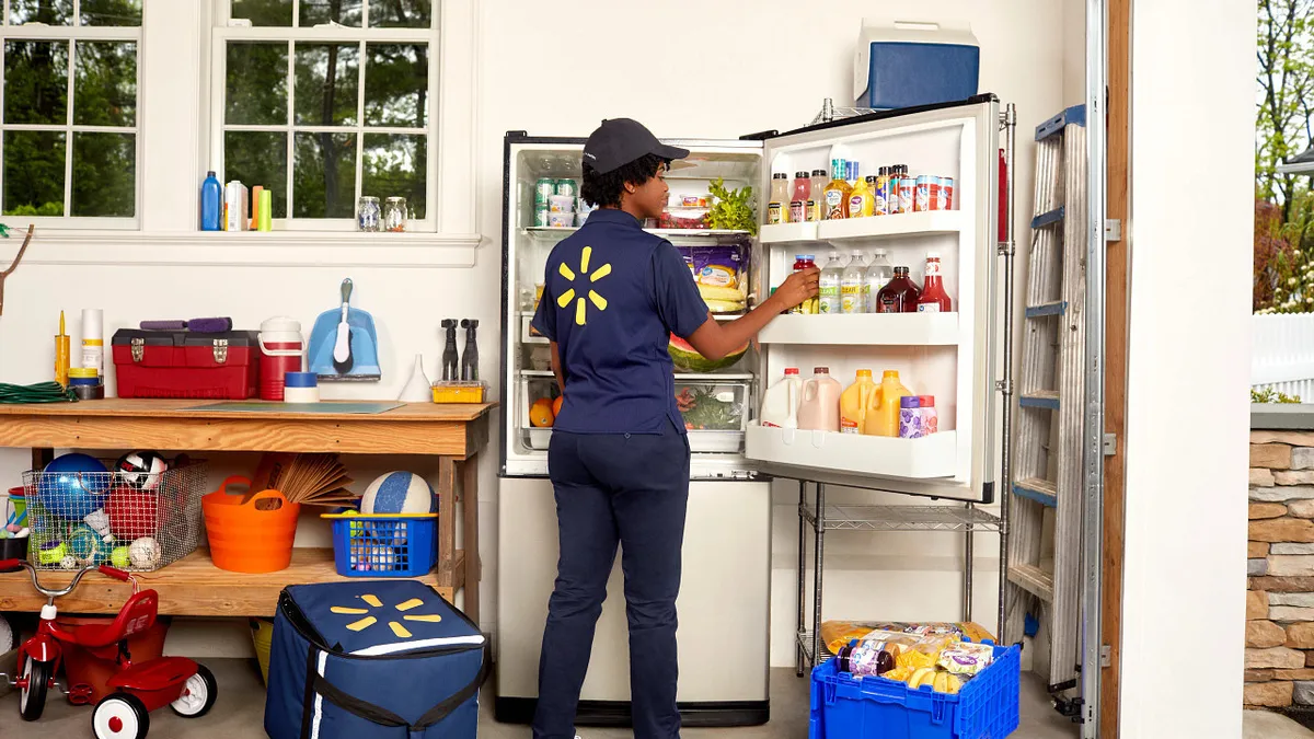 A Walmart worker stocking a fridge with food.