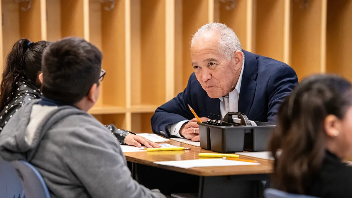 Houston Independent School District Superintendent Mike Miles sits at a table with younger students