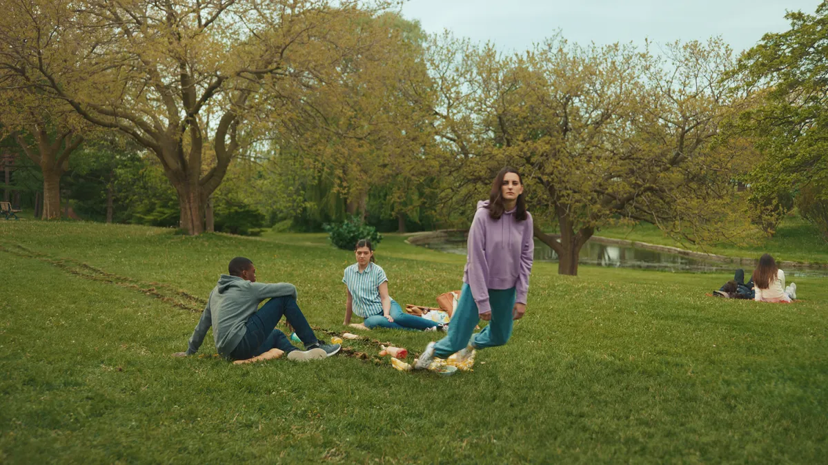 A woman drags her feet through a picnic in a commercial for NerdWallet