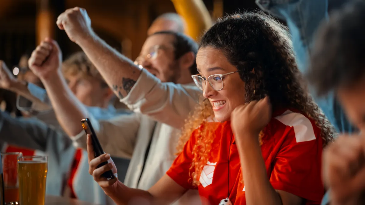 Portrait of an woman nervous about a sports bet on her smartphone.